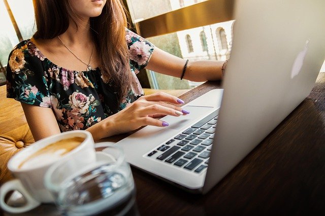 Femme qui travaille sur un ordinateur portable, tasse de café sur la table